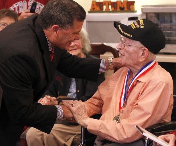 Rick Perales greeting a World War II veteran wearing his service medal